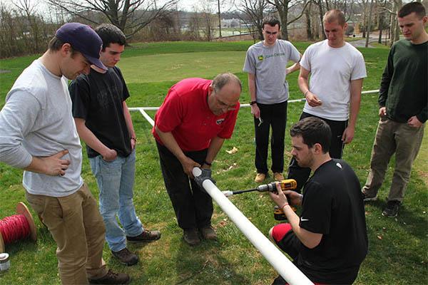 George Ley helps Delaware Valley University students install new irrigation in the university's research putting green. Photo by Delaware Valley University