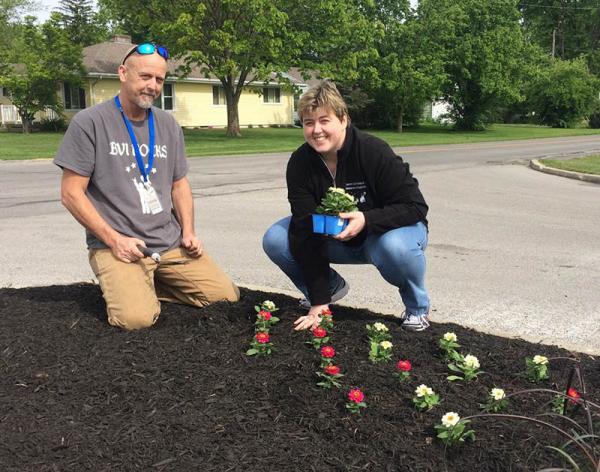 Tim Stumpp, left, greenhouse director for the Blanchard Valley Center, and one of the center's clients plant flowers recently at the entrance to Findlay Country Club.