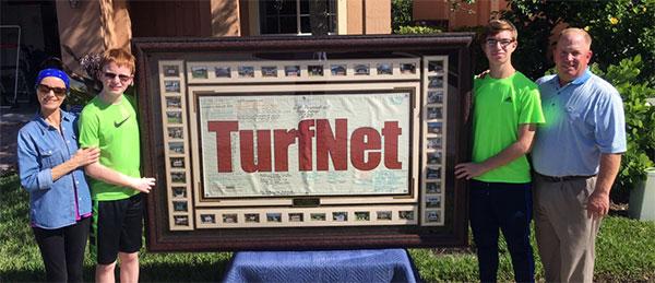 Peggy, Robert, Kevin and John Colo with a framed TurfNet banner, November 2017.