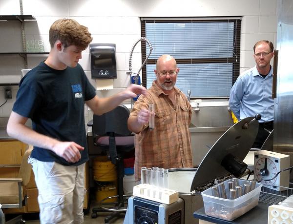 Travis Shaddox, Ph.D., far right, of the University of Florida looks on as lab worker Max Walkup, left, a Gainesville-area high school student, and Billy Crow, Ph.D., demonstrate the long process of extracting nematodes from soil samples.